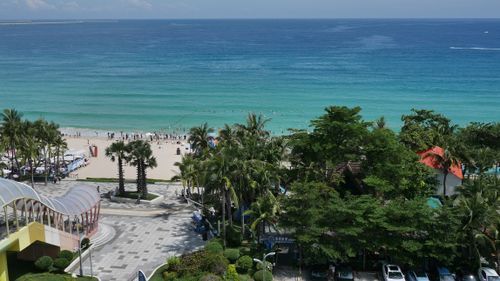 Free A vibrant beachfront scene in Sanya, Hainan, with lush greenery and clear waters. Stock Photo