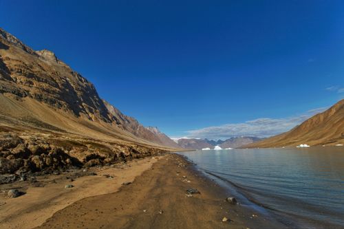 Free Stunning view of a remote Arctic landscape with mountains and icebergs under clear blue skies. Stock Photo