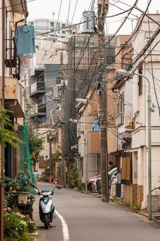 Discover a quaint Japanese street with hanging laundry, power lines, and a parked scooter.