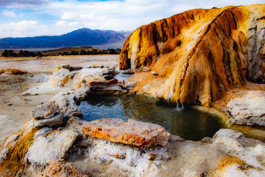 Vibrant and colorful hot spring amidst a barren geothermal landscape.