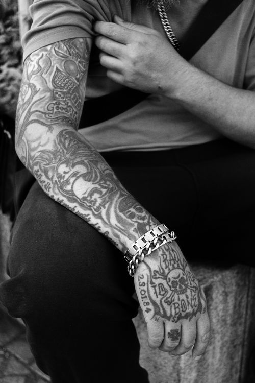 Free Black and white photo showcasing a tattooed arm and wrist with detailed designs and chain bracelet. Stock Photo