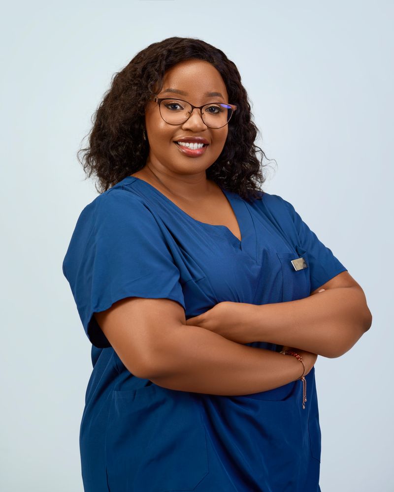 Portrait of Dr. Maya Okafor in navy scrubs, smiling with arms crossed