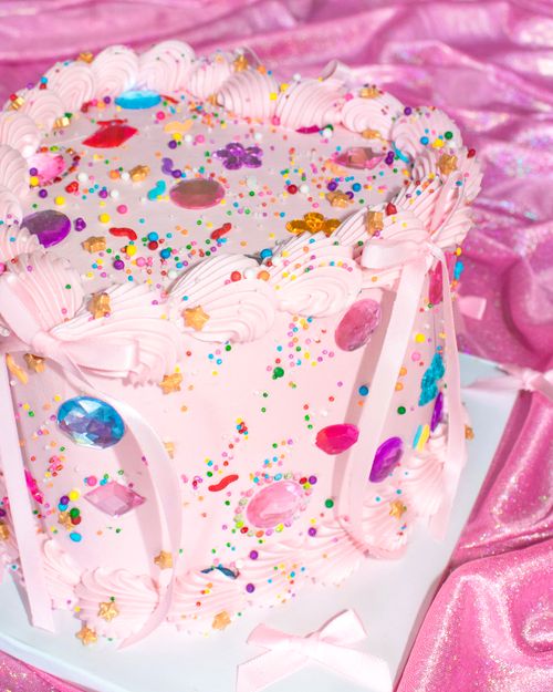Free A vibrant pink cake adorned with colorful gems and sprinkles, perfect for a birthday celebration. Stock Photo