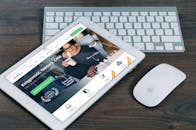 一台平板电脑正打开金融网站，旁边配有白色键盘和鼠标，非常适合科技主题的股票图片