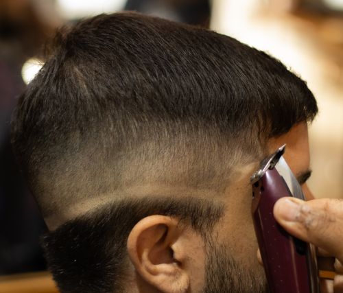 Free A barber uses clippers to perfect a professional fade haircut in a modern salon. Stock Photo