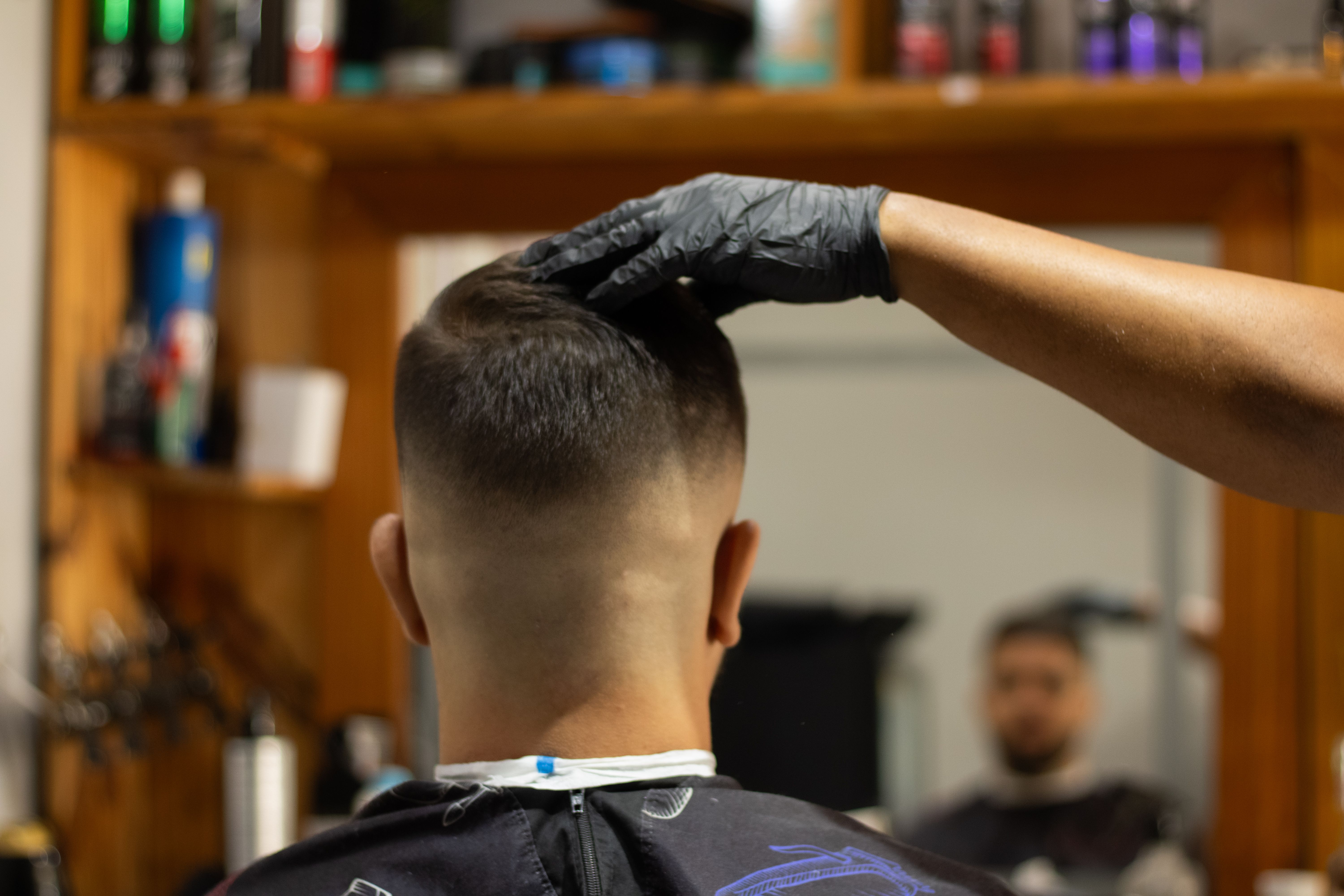 Barber styling a client's hair with precision in a cozy, modern salon.