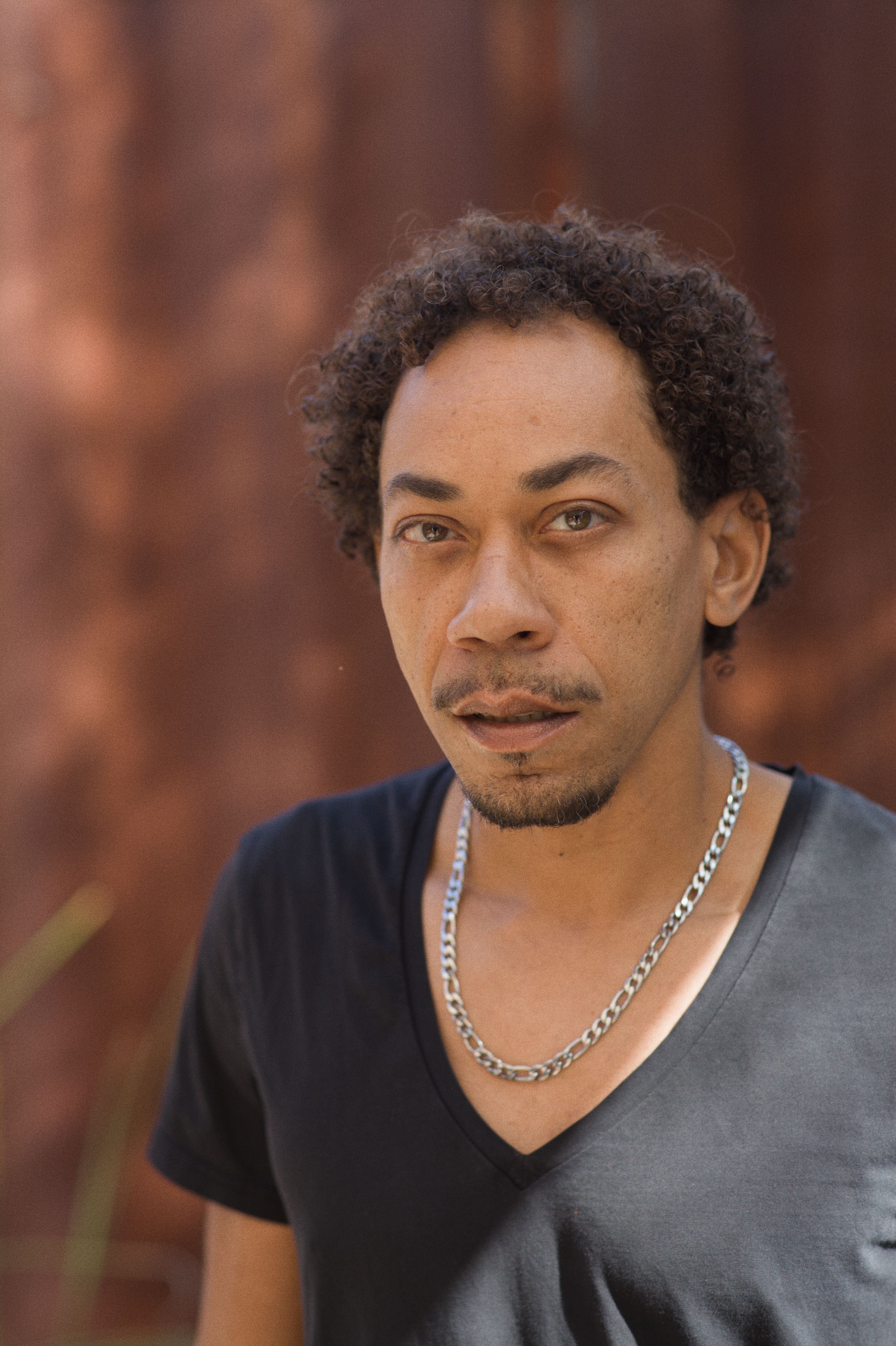 Close-up portrait of a man with natural background, showcasing casual style and expression.