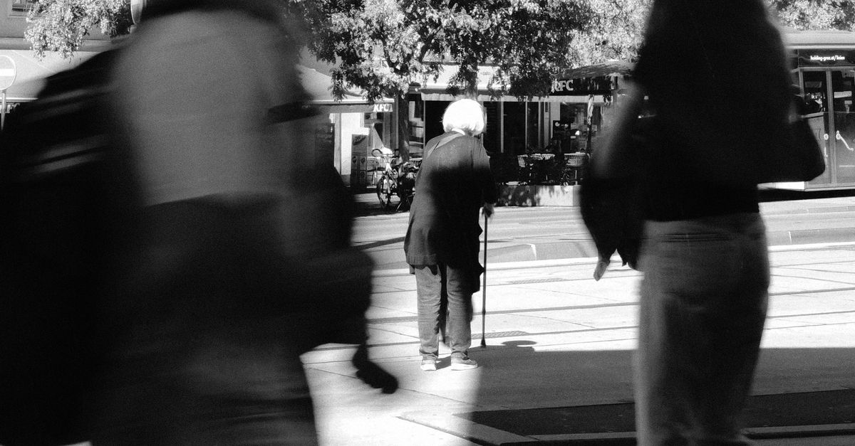 Black and white street photo capturing urban life with motion blur.