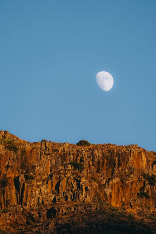 Free Captivating view of the moon above volcanic cliffs in Valle Gran Rey, Canary Islands. Stock Photo