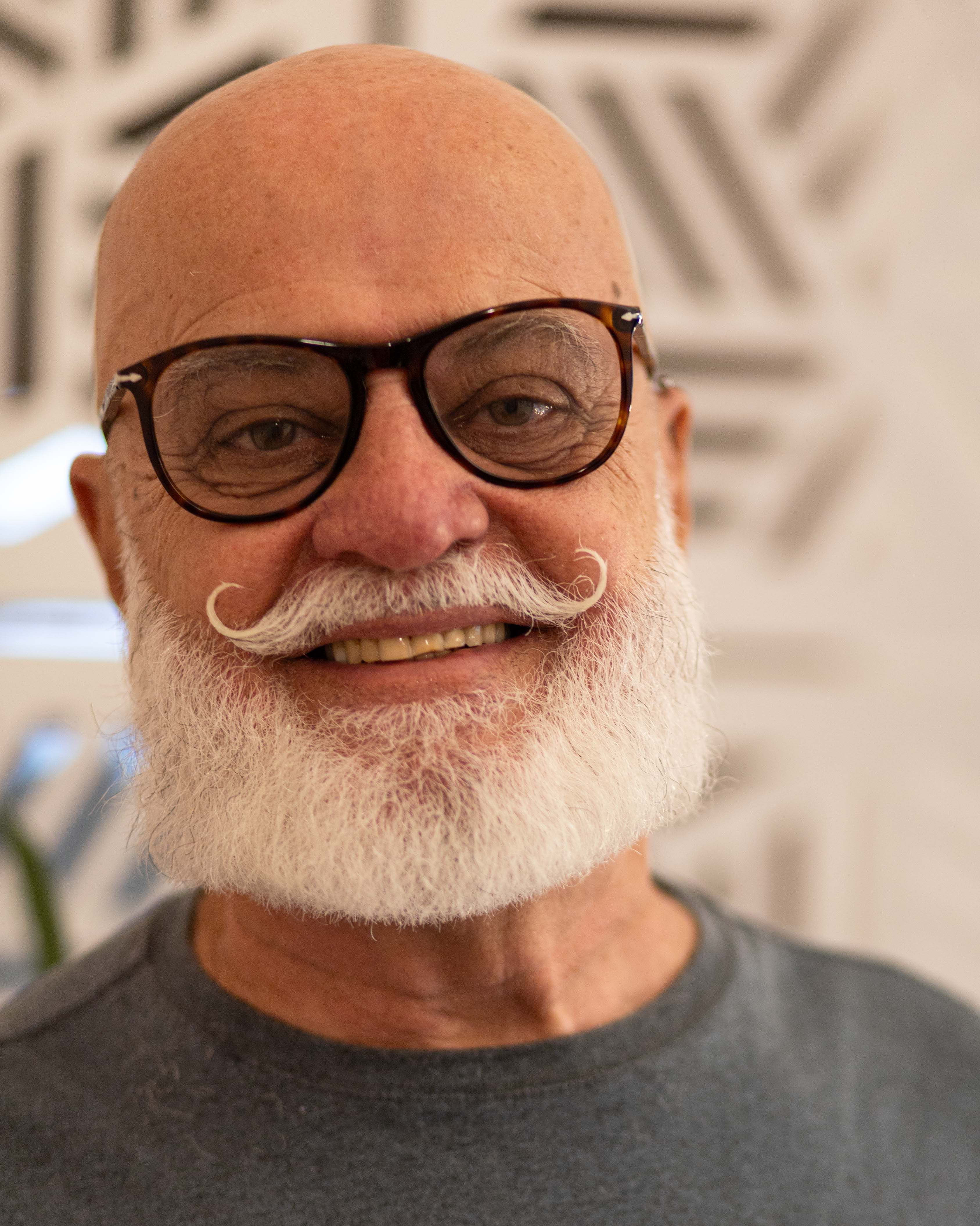 Portrait of a cheerful senior man with glasses and a stylish beard indoors.