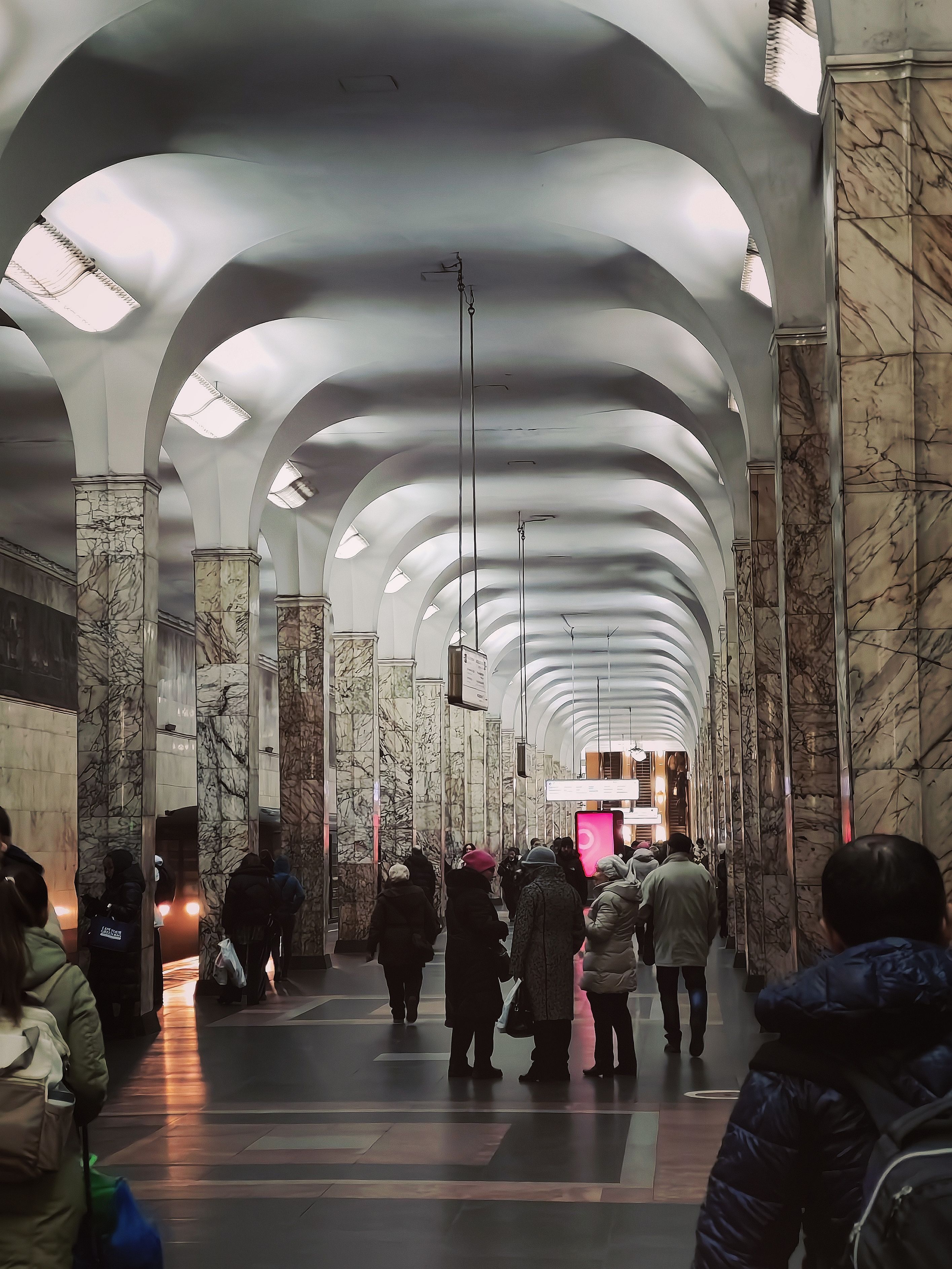 Marble-adorned Moscow metro station bustling with winter-clad commuters.