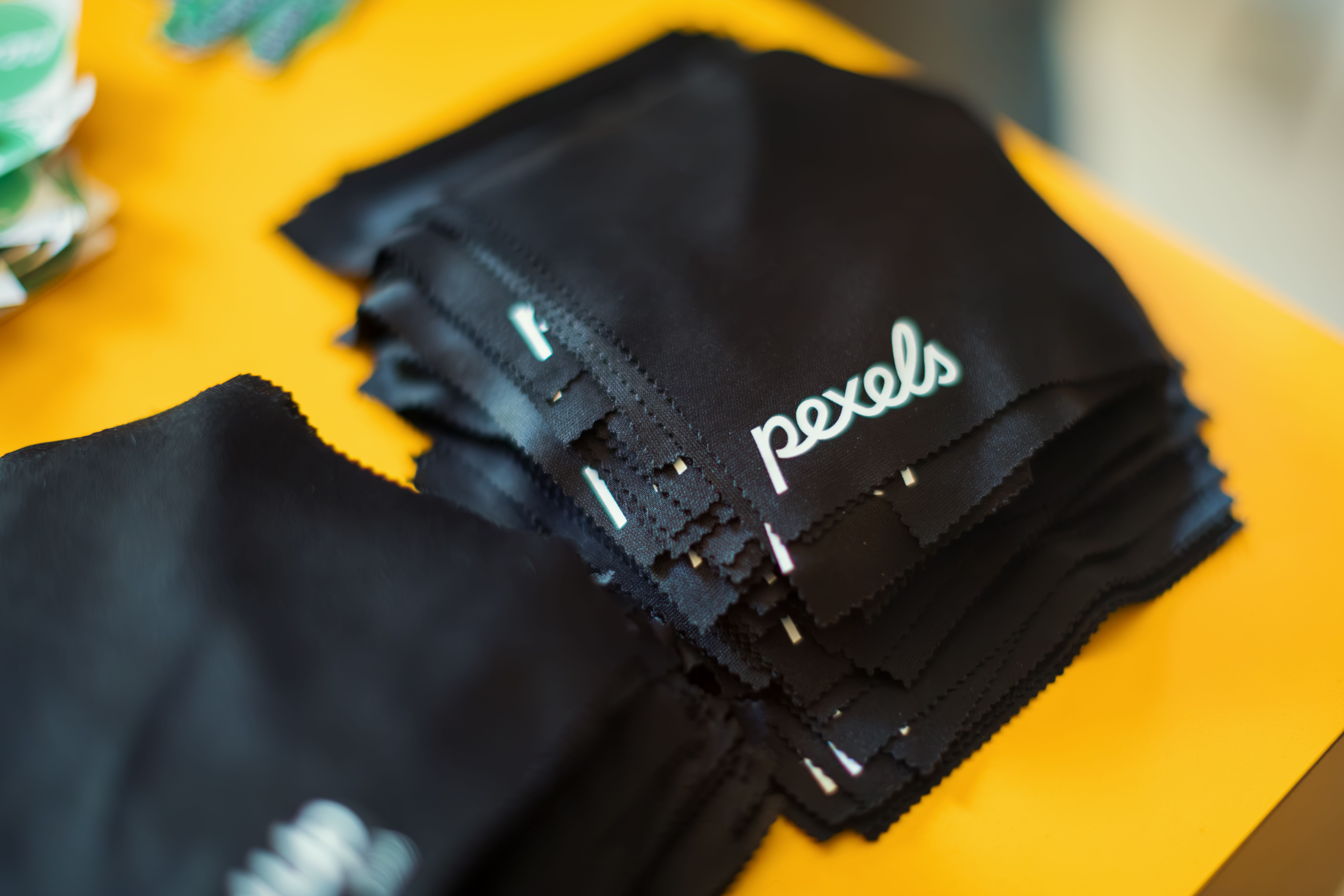Close-up view of a stack of black microfiber cloths with "pexels" logo on a yellow background.
