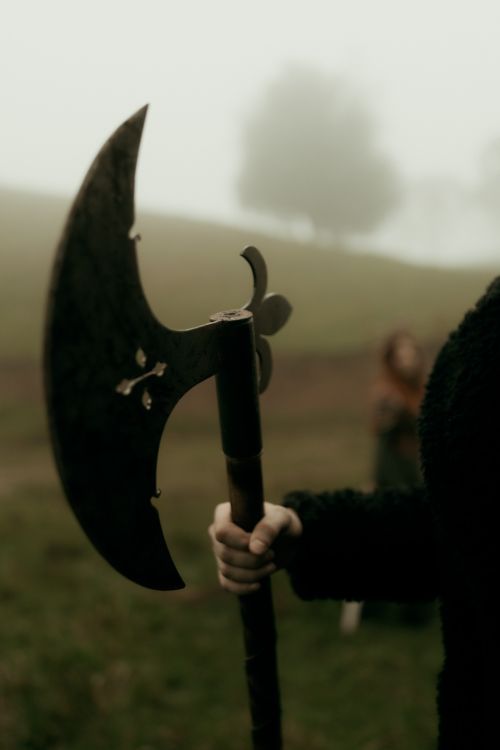 Free A person in medieval attire holds a large axe in a misty field, evoking a historic atmosphere. Stock Photo