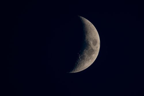 Free A detailed image of a crescent moon illuminated against a dark night sky. Stock Photo