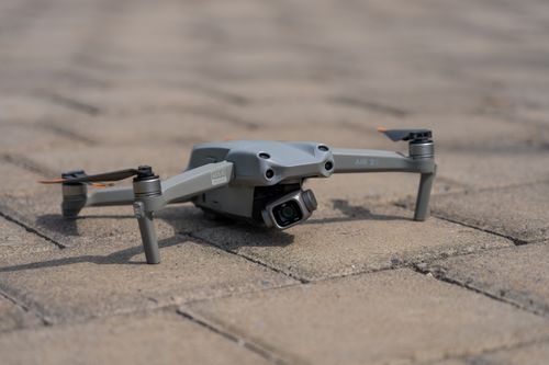 Free Close-up of a compact drone resting on a paved brick surface, ready for flight. Stock Photo