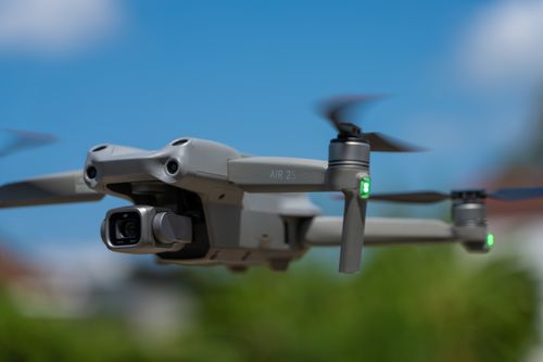 Free A close-up view of a modern drone in flight with a clear blue sky background, showcasing its intricate details. Stock Photo