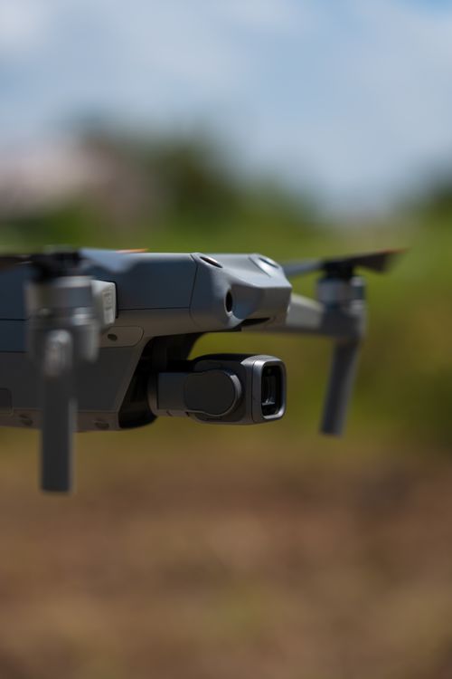Free Close-up of a modern drone hovering outdoors with blurred landscape background. Stock Photo