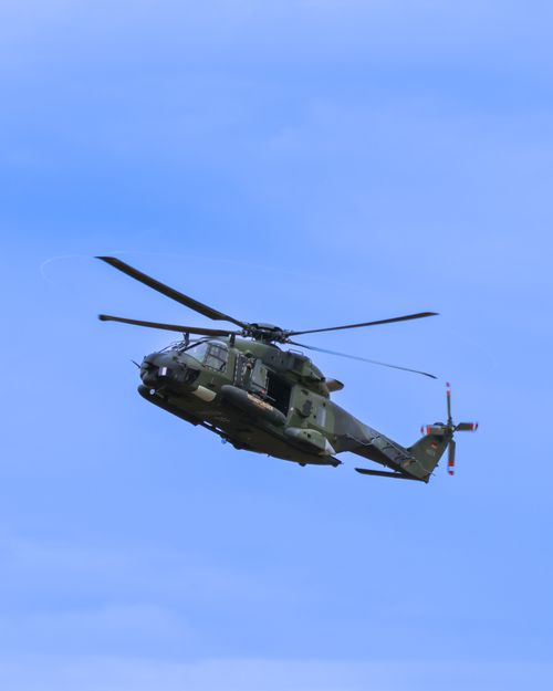 Free A military helicopter flying against a clear blue sky, showcasing dynamic aviation in action. Stock Photo