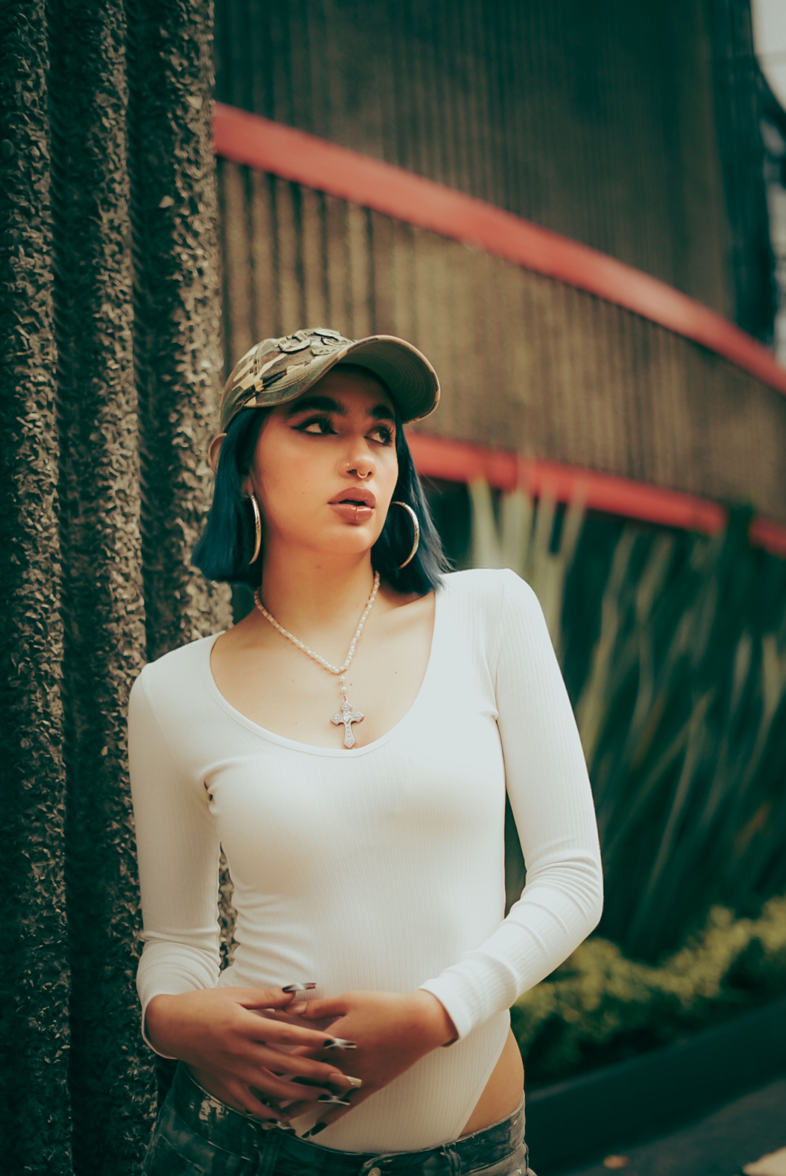 Young woman in a casual outfit posing outdoors with modern architecture in the background.