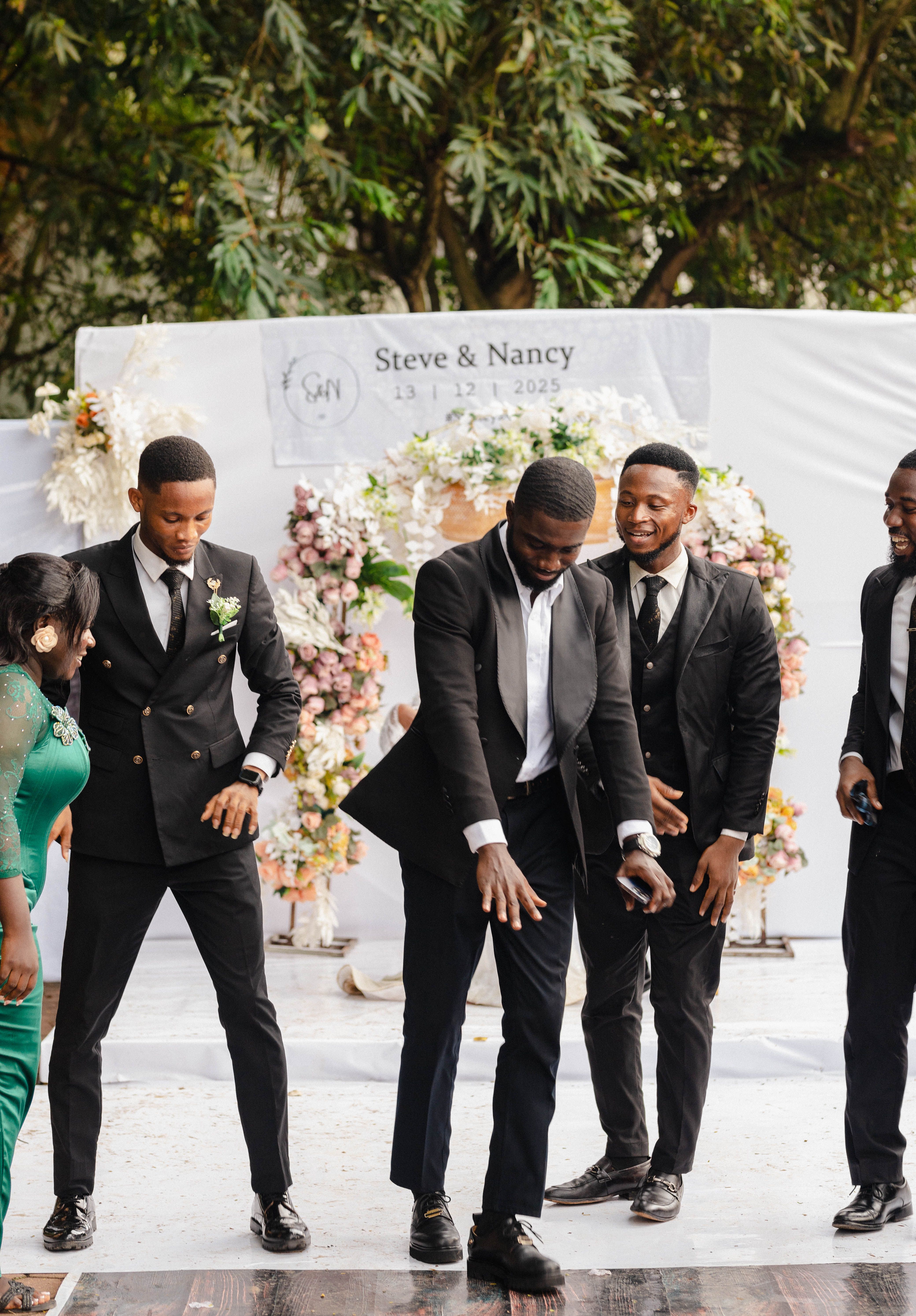Guests joyfully dance at outdoor wedding near elegant floral backdrop.