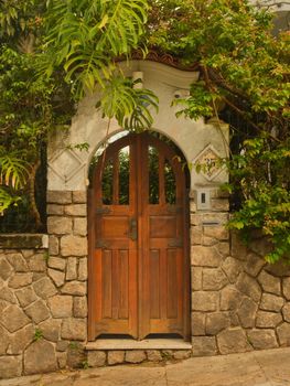 An inviting stone archway with a rustic wooden door surrounded by lush greenery.