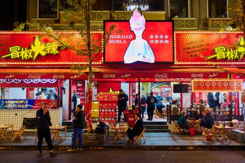 Free A bustling Sichuan restaurant scene at night with lively street atmosphere and vibrant signage. Stock Photo