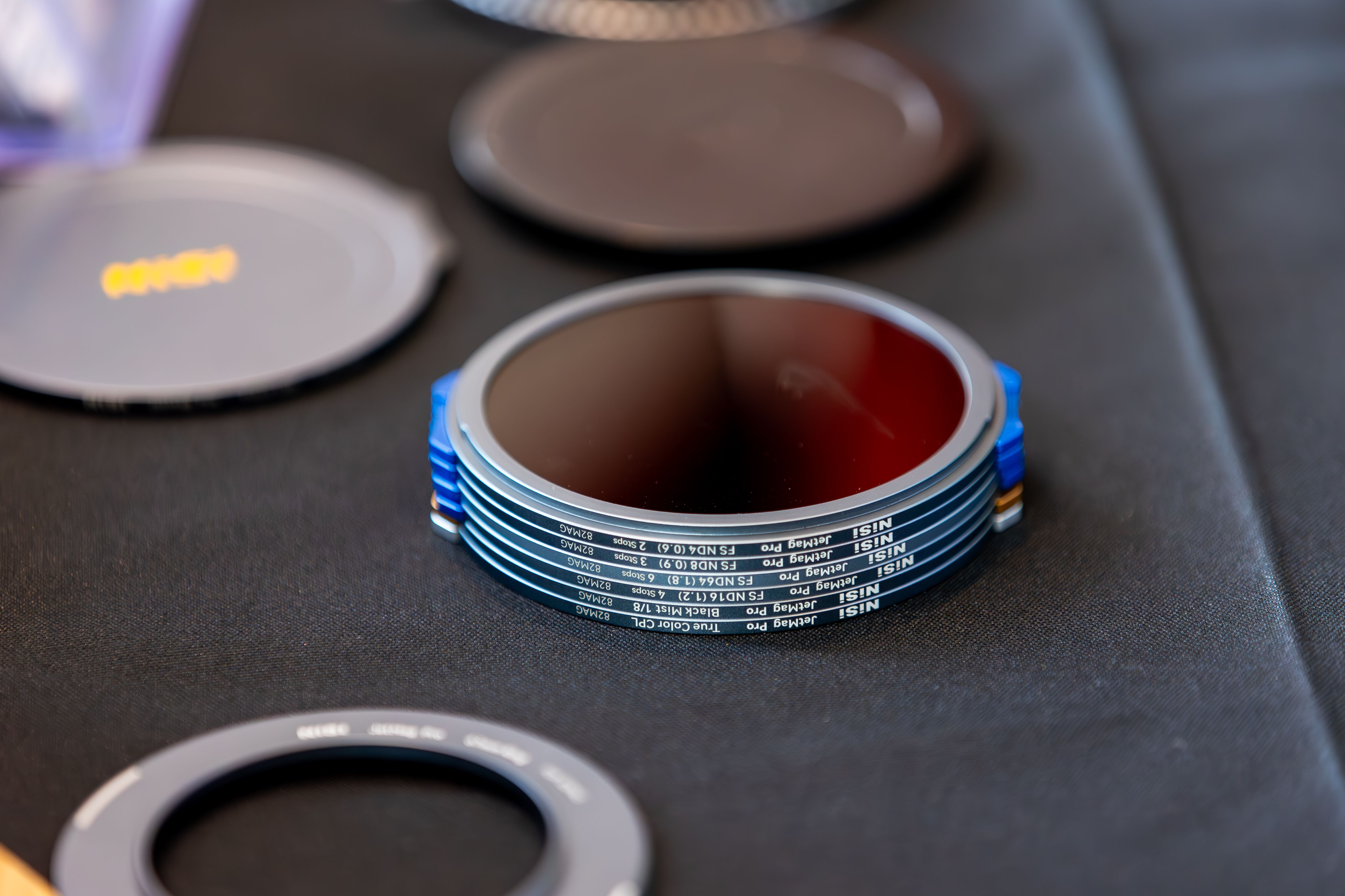 Close-up of professional camera lens filters laid out on a dark surface, showcasing various designs and details.