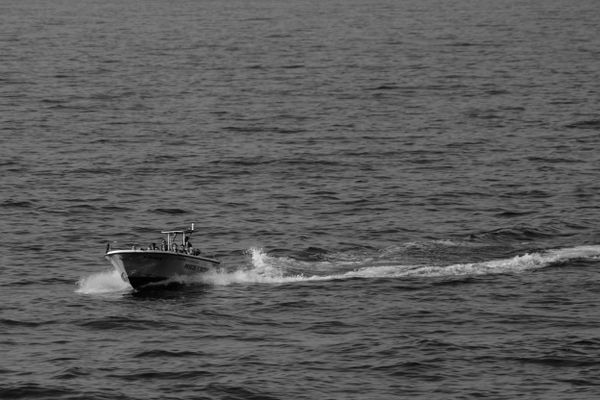 Bateau de pêche et de plongée glissant sur la mer, près de Ribadeo, en noir et blanc