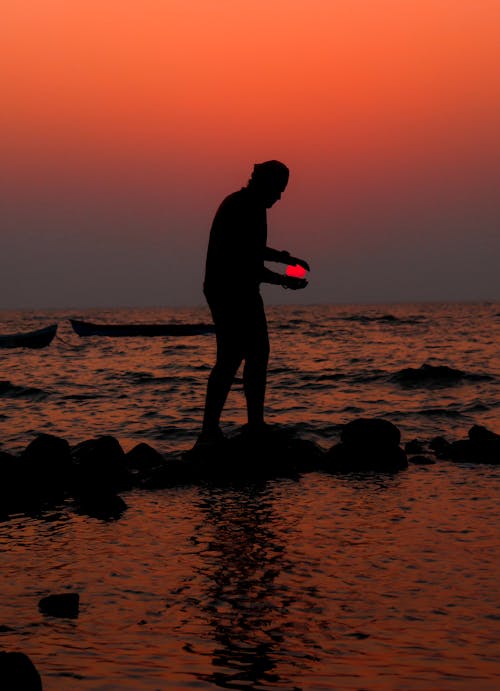 日没時にビーチに立っている男のシルエット