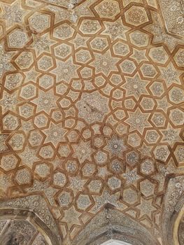 Detailed geometric patterns on an ornate ceiling in New Delhi, India, showcasing traditional architectural artistry.