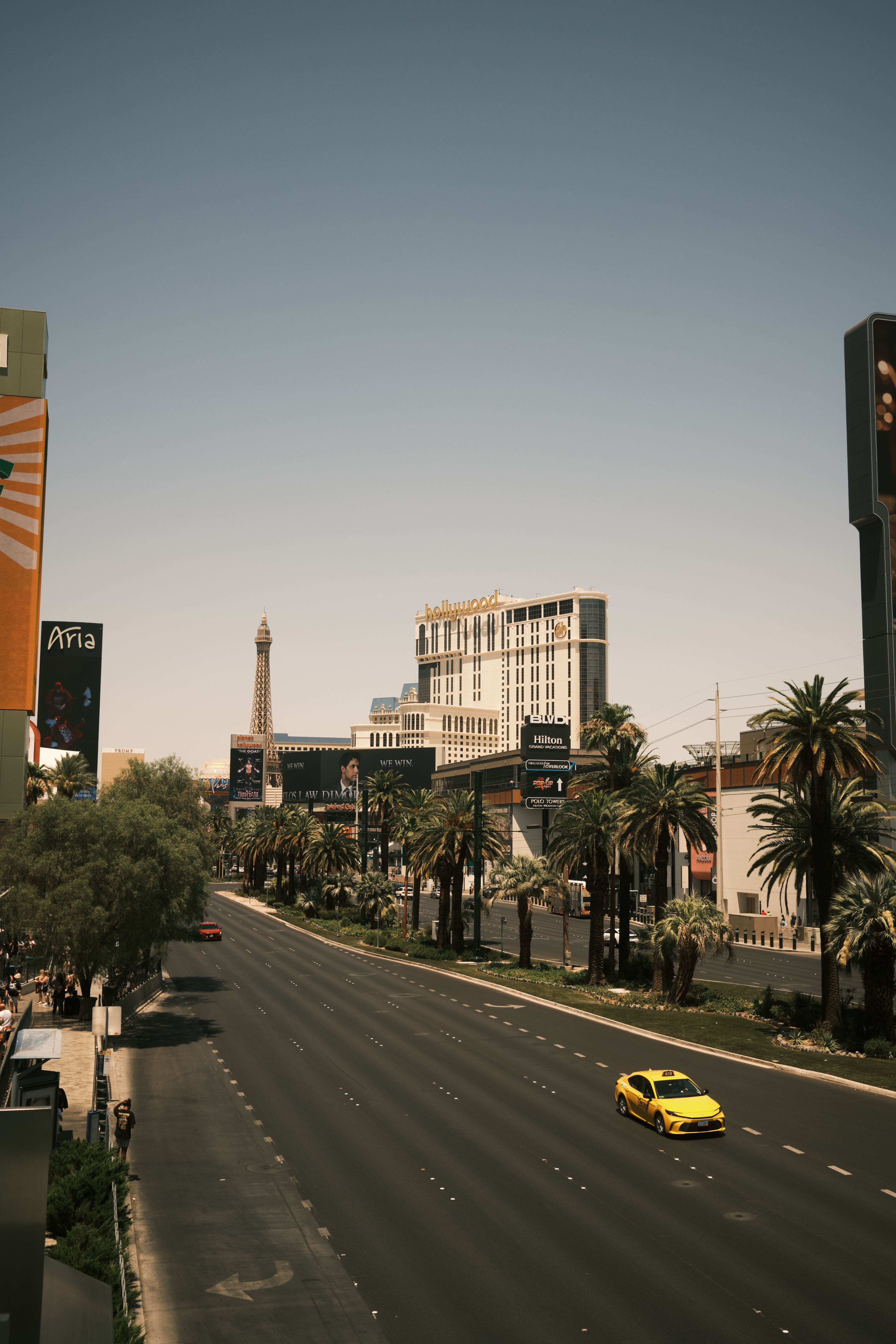 A bright sunny view of Las Vegas Strip with the Eiffel Tower replica and palm-lined roads.