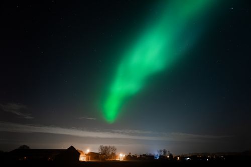 Free Stunning image of a green aurora dancing over a peaceful night landscape with visible horizon. Stock Photo