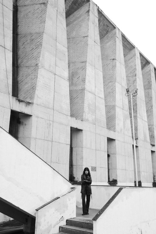 Free Black and white image of a person standing beside a modern concrete building. Stock Photo