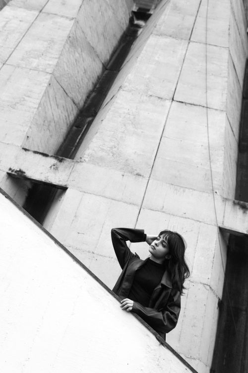 Free Moody black and white portrait of a woman by striking modern architecture. Stock Photo