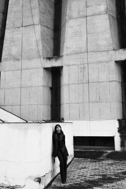 Free A monochrome shot of a woman leaning on a concrete structure, conveying an urban mood. Stock Photo
