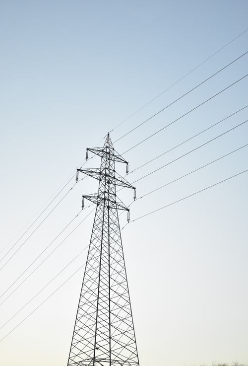 Free A tall electrical power transmission tower against a clear blue sky, symbolizing energy and infrastructure. Stock Photo