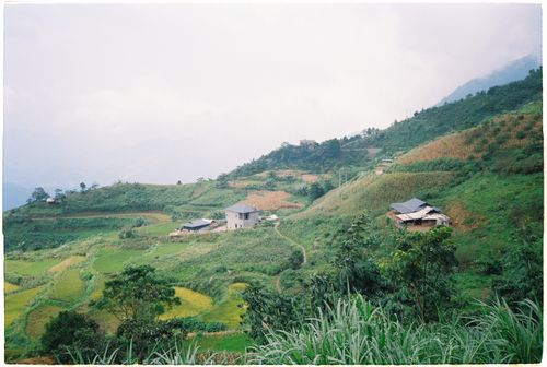Free A serene view of rural hills and farmland with scattered homes under a cloudy sky. Stock Photo