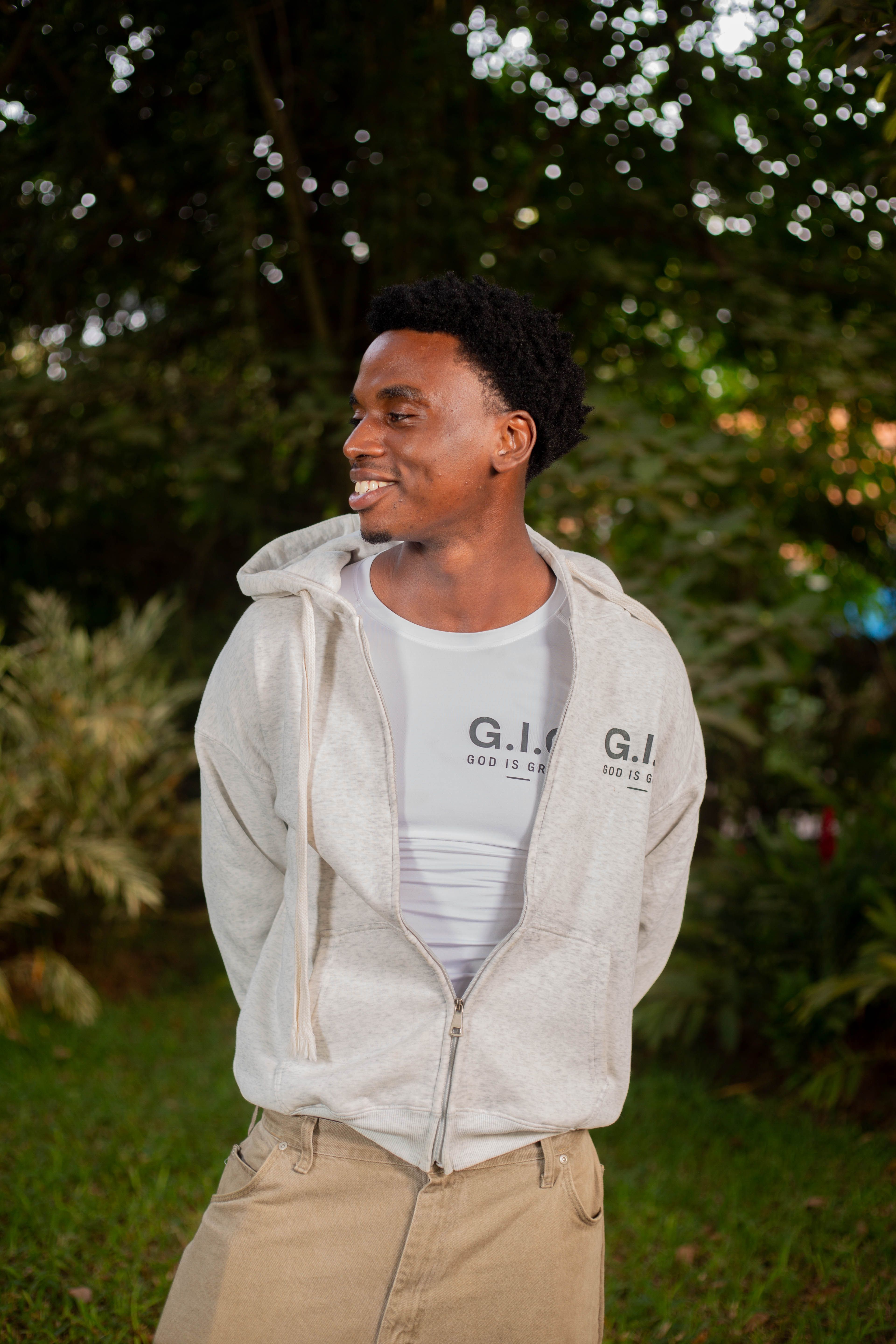 A cheerful man smiles while outdoors in a casual hoodie and t-shirt.