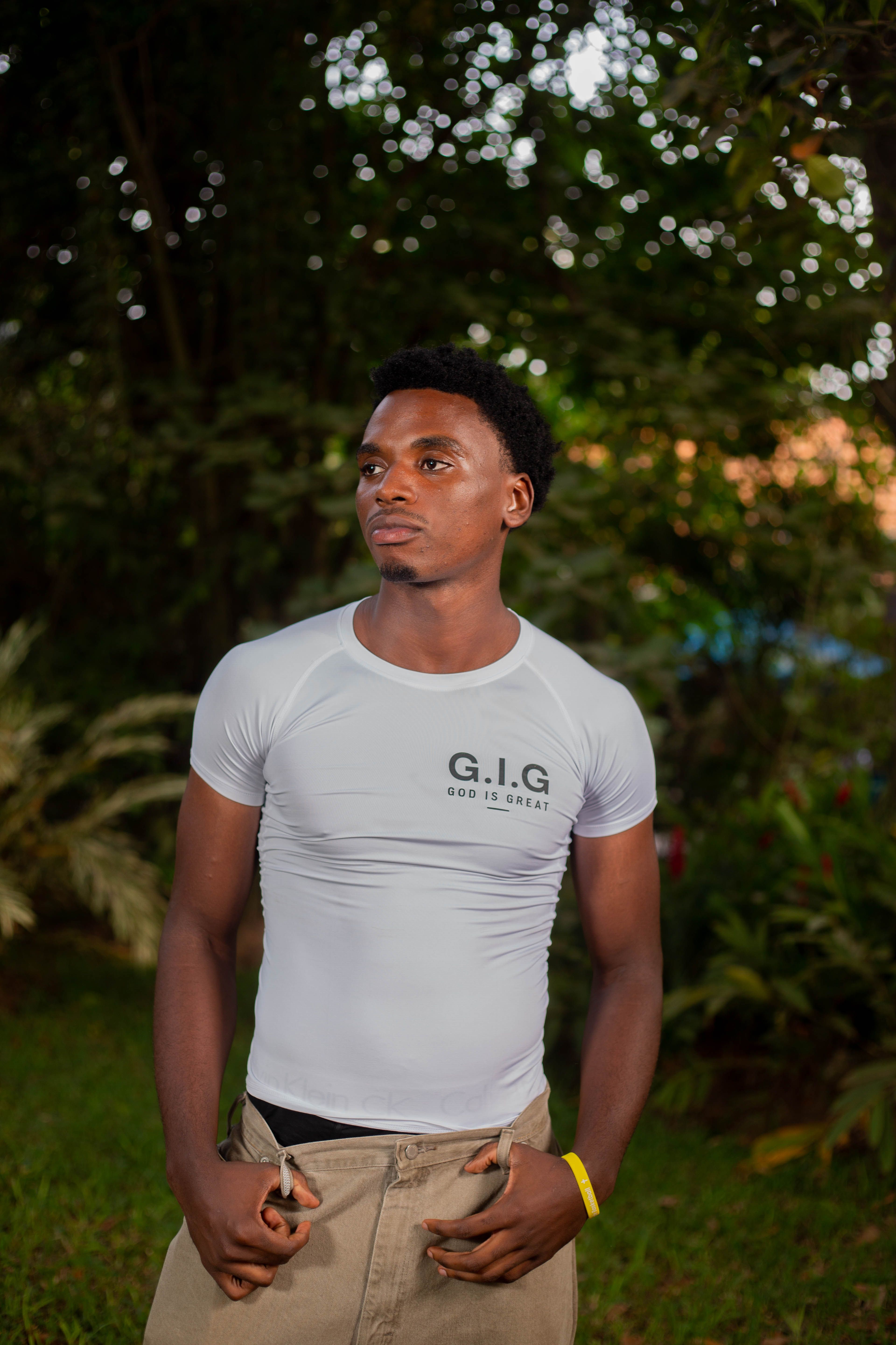 Portrait of a young man in a G.I.G. t-shirt standing outdoors with a thoughtful expression.