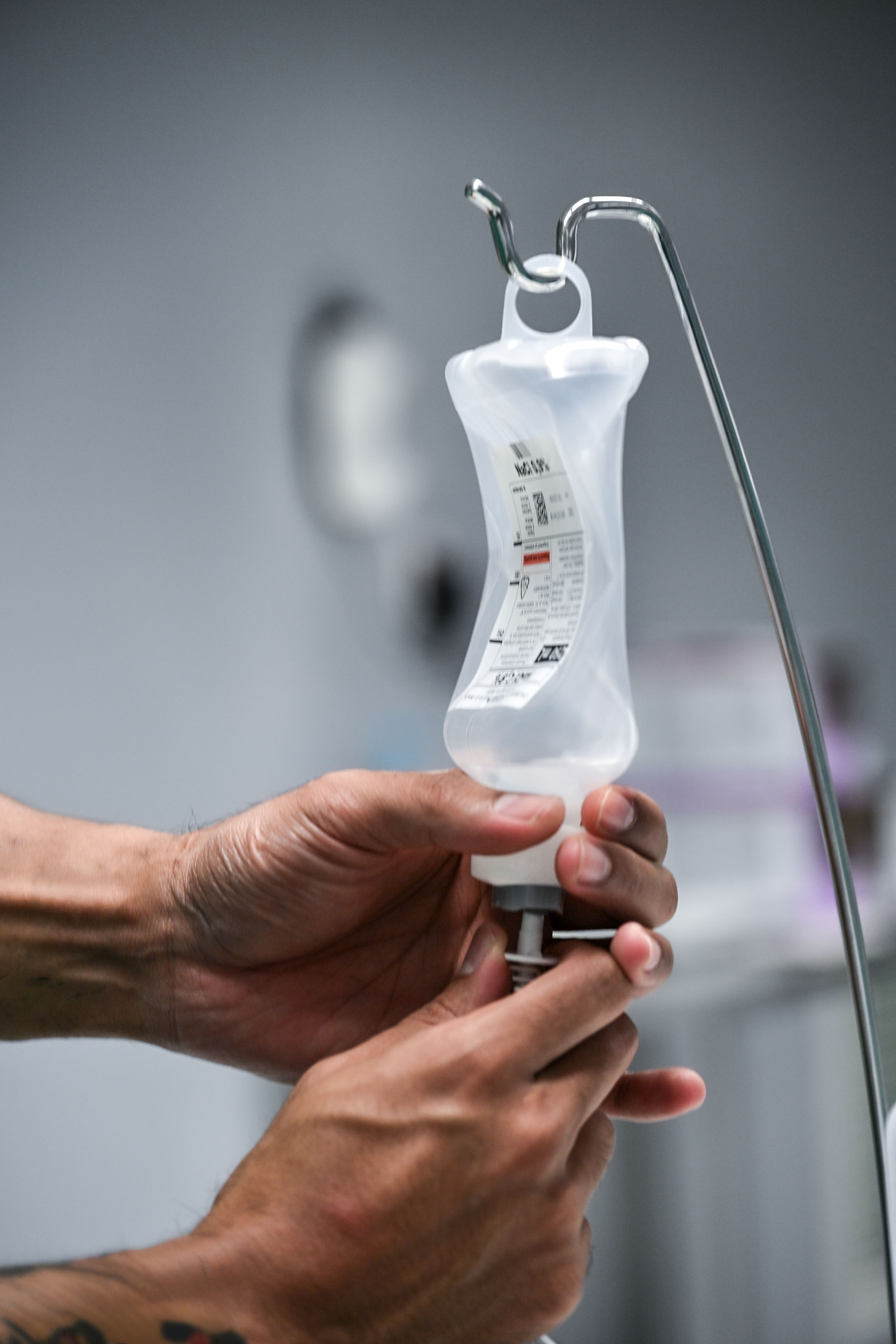 A focused shot of hands adjusting an IV drip in a hospital setting, highlighting precision and care.