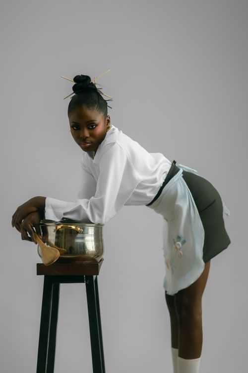 Free Elegant female chef in uniform leaning over a pot, striking a stylish pose. Stock Photo