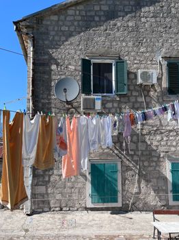 A rustic stone house facade with colorful laundry hanging under the bright sun.