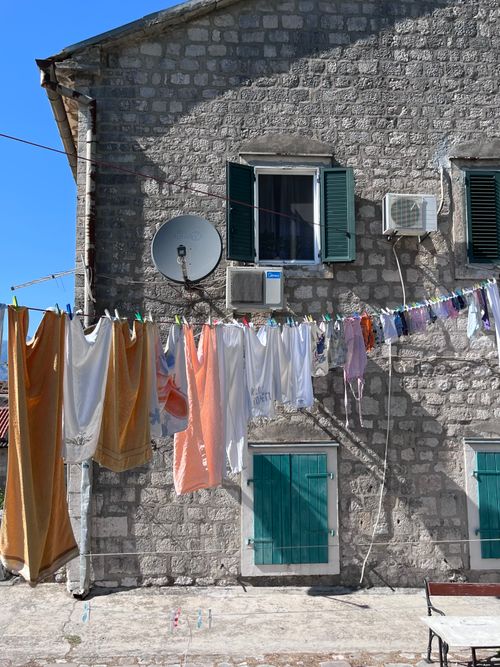 Free A rustic stone house facade with colorful laundry hanging under the bright sun. Stock Photo