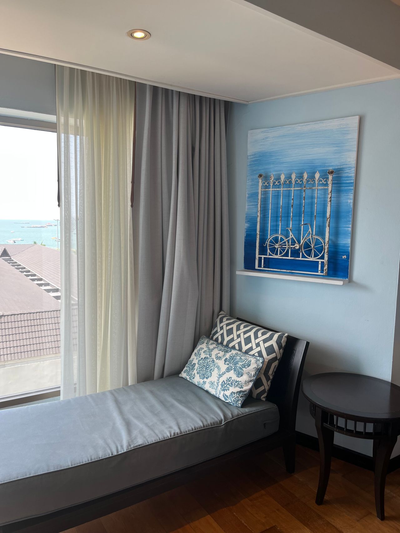 Daybed reading nook with blue pillows beside a bright window overlooking the sea