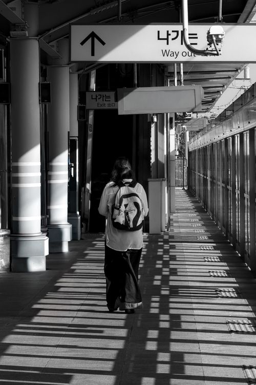 Free A solitary figure in a subway station, highlighted in a dramatic interplay of light and shadow, heading toward the exit. Stock Photo