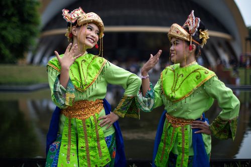 Free Two women in traditional Indonesian costume performing a dance outdoors in Jakarta, Indonesia. Stock Photo