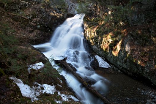 A beautiful waterfall cascades down mossy rocks in a peaceful forest scene.