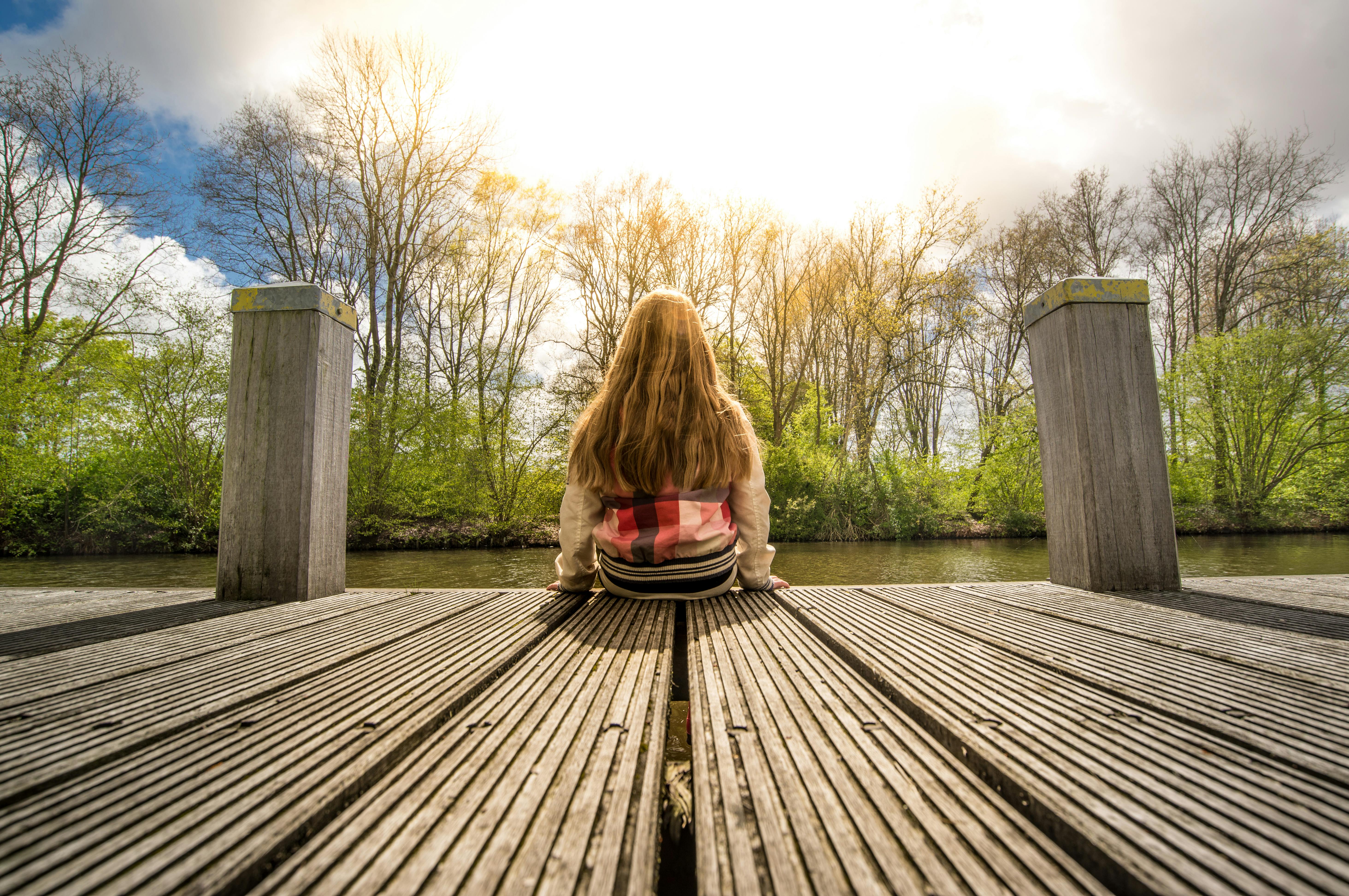 Woman with coffee cup standing on jetty over lake stock photo