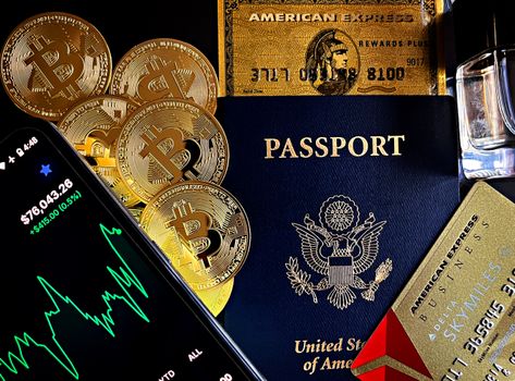 A flat lay of bitcoins, a US passport, credit cards, and a stock market app display.