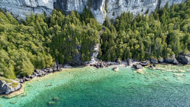 Stunning aerial view of the Georgian Bay cliffs and lush forest by the turquoise shoreline.